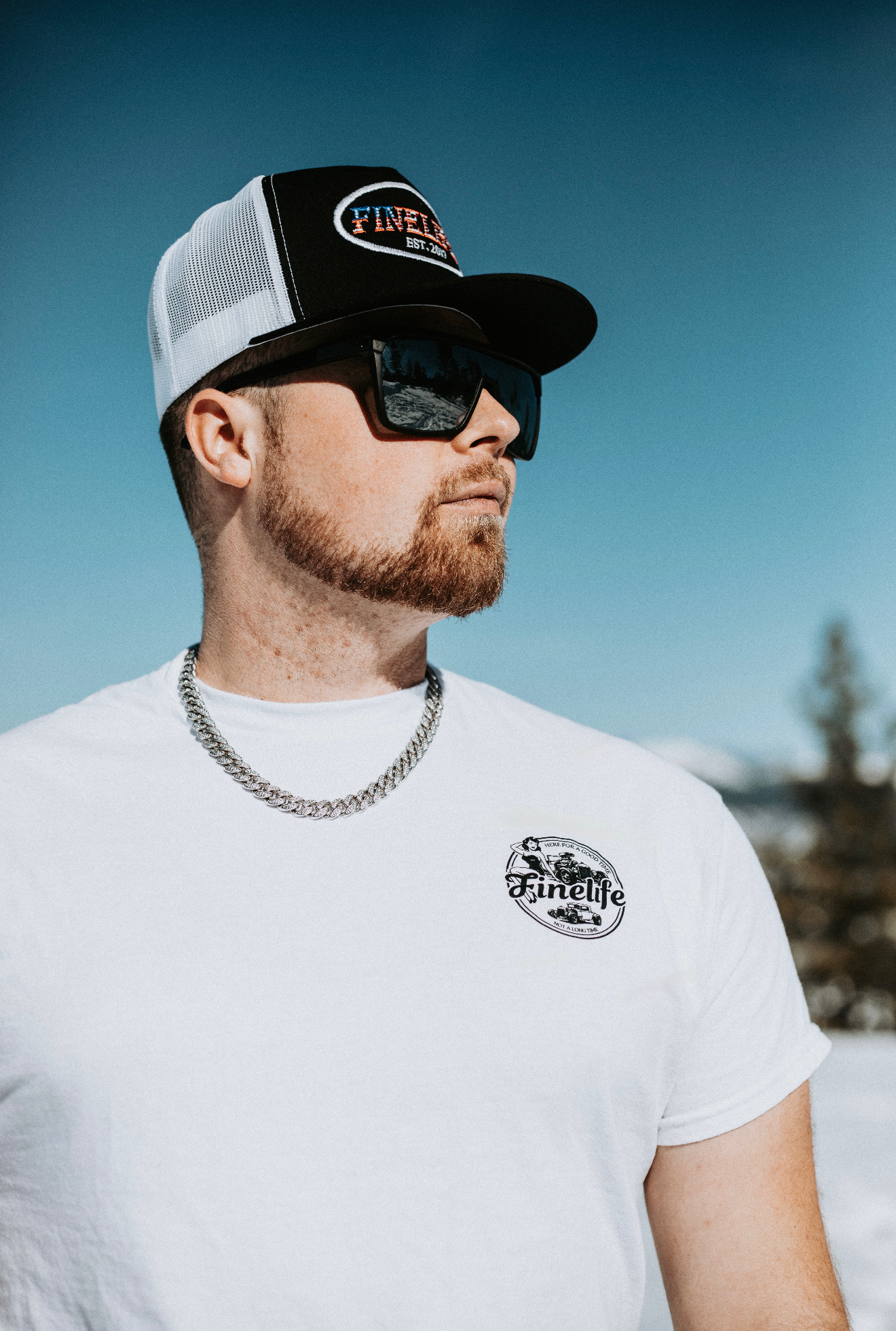 Man wearing a cap and sunglasses with a clear blue sky in the background